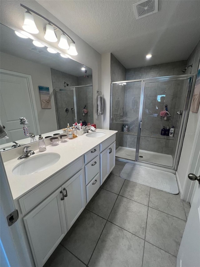 bathroom with tile patterned floors, walk in shower, a textured ceiling, and vanity