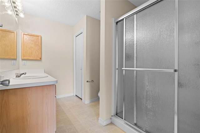 bathroom featuring toilet, a shower with door, a textured ceiling, and vanity