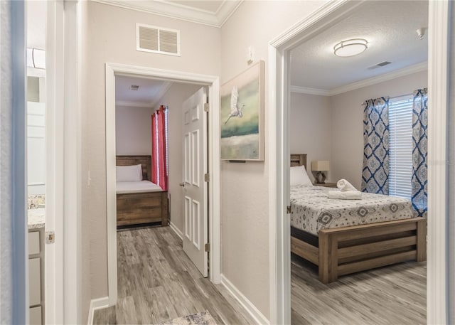 corridor with ornamental molding, a textured ceiling, and light hardwood / wood-style floors