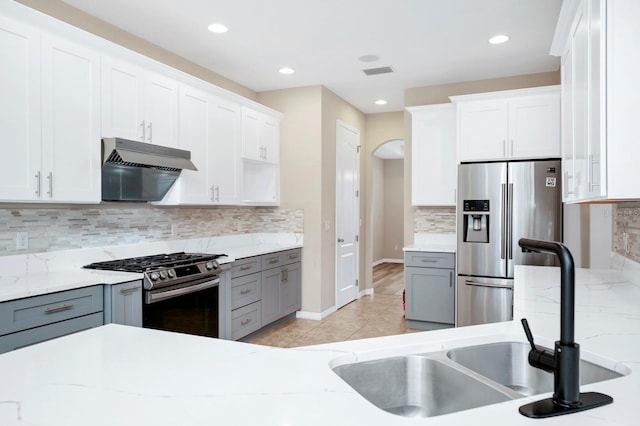 kitchen with gray cabinets, white cabinetry, appliances with stainless steel finishes, and backsplash