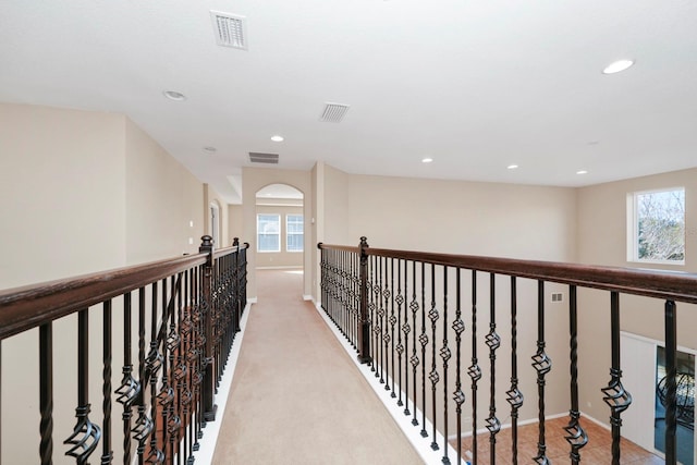 hall with plenty of natural light and light carpet