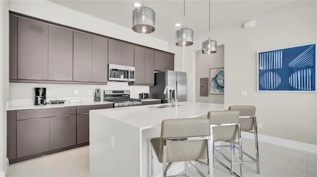 kitchen featuring hanging light fixtures, light tile patterned floors, a kitchen island with sink, stainless steel appliances, and a breakfast bar area