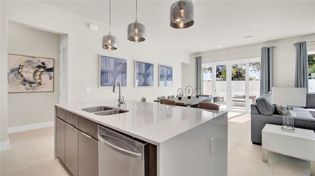 kitchen featuring an island with sink, light tile patterned floors, sink, decorative light fixtures, and dishwasher