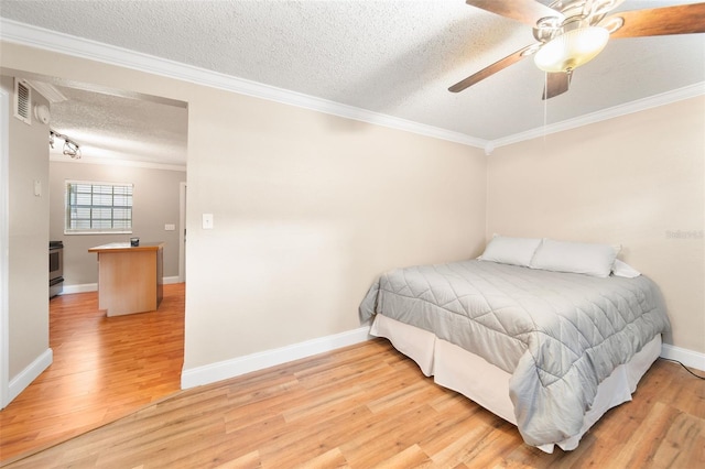 bedroom with light wood-type flooring, ceiling fan, crown molding, and a textured ceiling