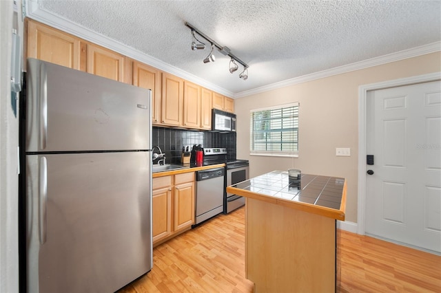 kitchen featuring light brown cabinetry, light hardwood / wood-style flooring, tile countertops, stainless steel appliances, and ornamental molding