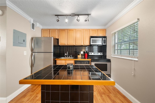 kitchen featuring light hardwood / wood-style flooring, appliances with stainless steel finishes, tile counters, tasteful backsplash, and a textured ceiling