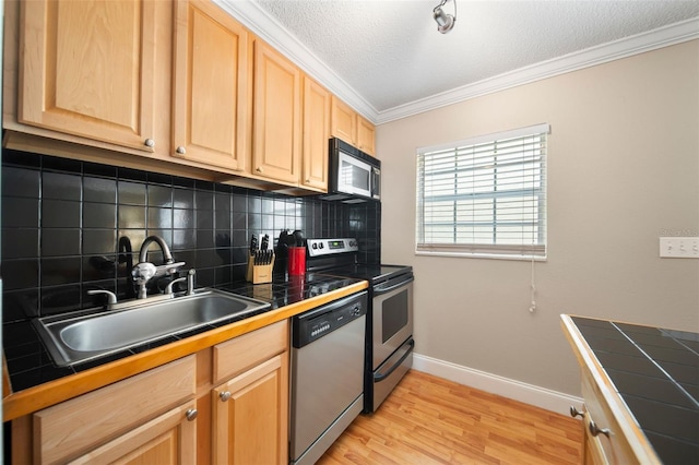 kitchen with tile counters, sink, appliances with stainless steel finishes, and light hardwood / wood-style floors