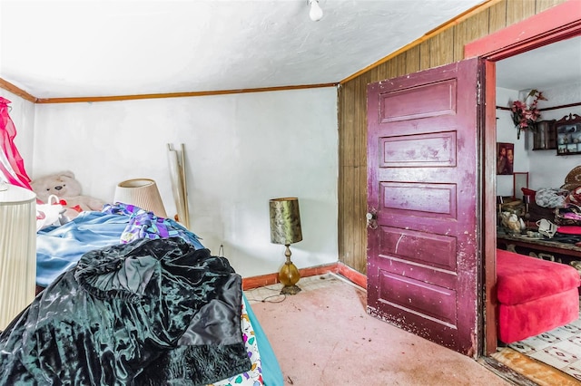 carpeted bedroom featuring wood walls and crown molding