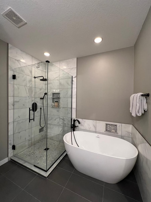 bathroom with tile walls, separate shower and tub, a textured ceiling, and tile patterned floors