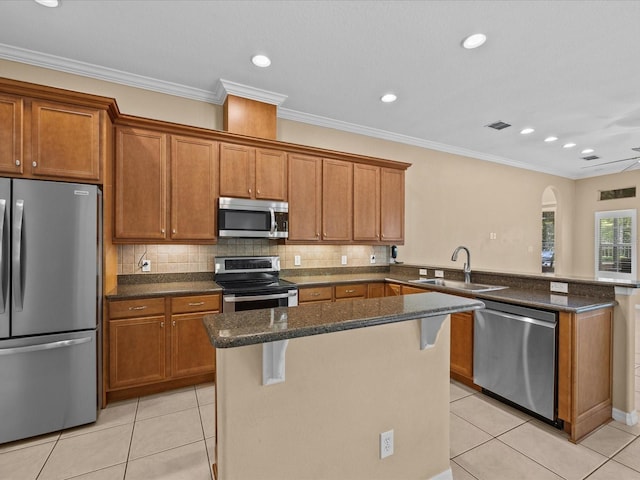 kitchen featuring a peninsula, light tile patterned floors, appliances with stainless steel finishes, and a sink