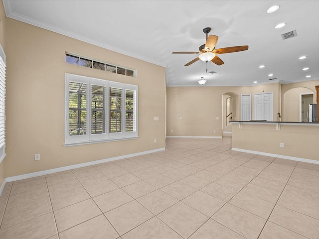 spare room featuring arched walkways, a ceiling fan, visible vents, and crown molding