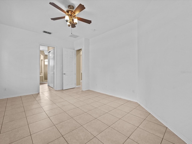 spare room featuring light tile patterned floors, baseboards, visible vents, and a ceiling fan