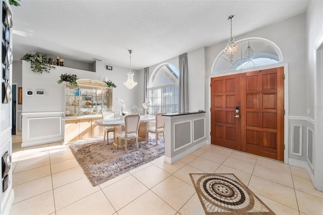 entryway featuring a notable chandelier, a high ceiling, a textured ceiling, and light tile patterned floors