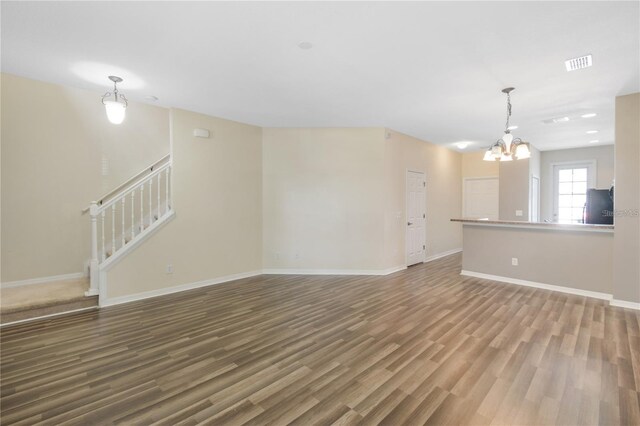 unfurnished living room with a notable chandelier and wood-type flooring