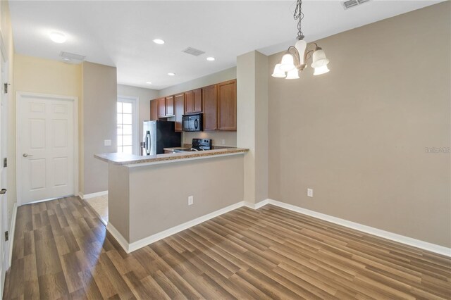 kitchen with kitchen peninsula, pendant lighting, black appliances, dark hardwood / wood-style floors, and a notable chandelier