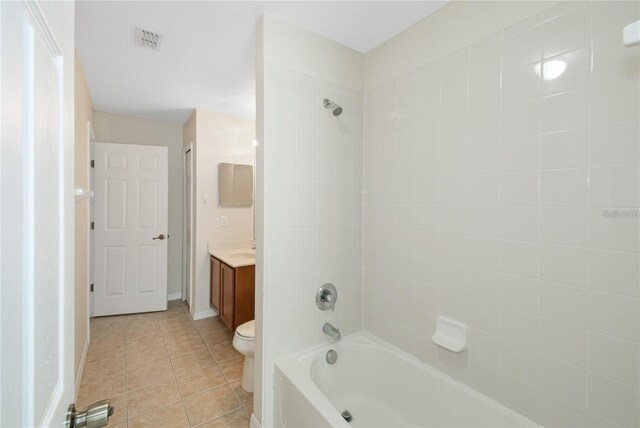 full bathroom with tiled shower / bath combo, tile patterned flooring, vanity, and toilet