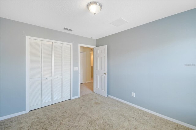 unfurnished bedroom with light carpet and a closet