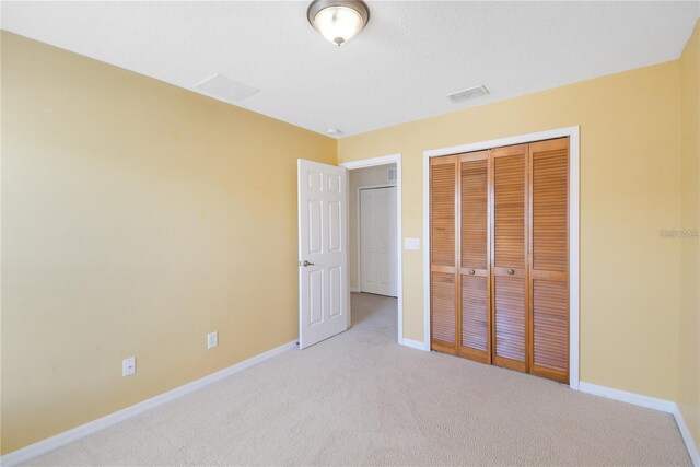 unfurnished bedroom with light carpet and a closet