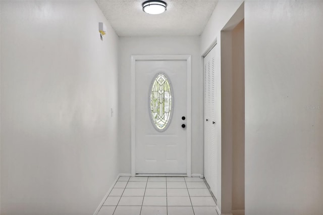 doorway to outside featuring a textured ceiling and light tile patterned floors