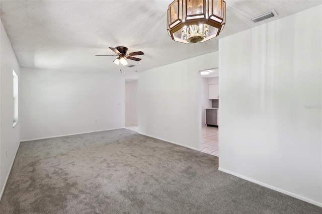 empty room featuring light carpet, a textured ceiling, and ceiling fan