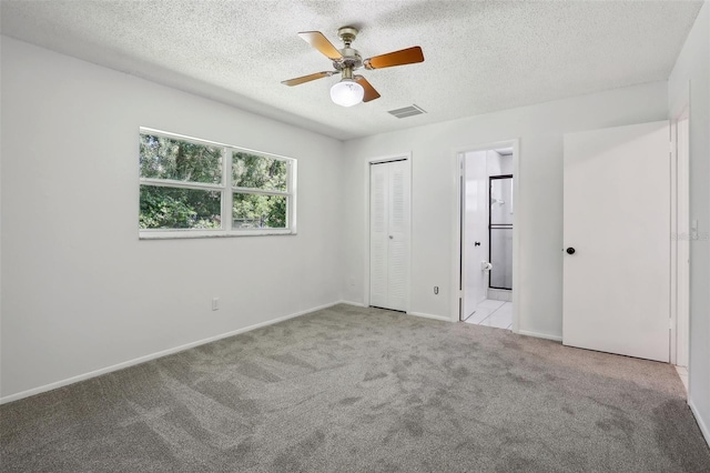 unfurnished bedroom with a closet, ceiling fan, light carpet, and a textured ceiling