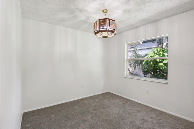 spare room with dark carpet, a notable chandelier, and a textured ceiling