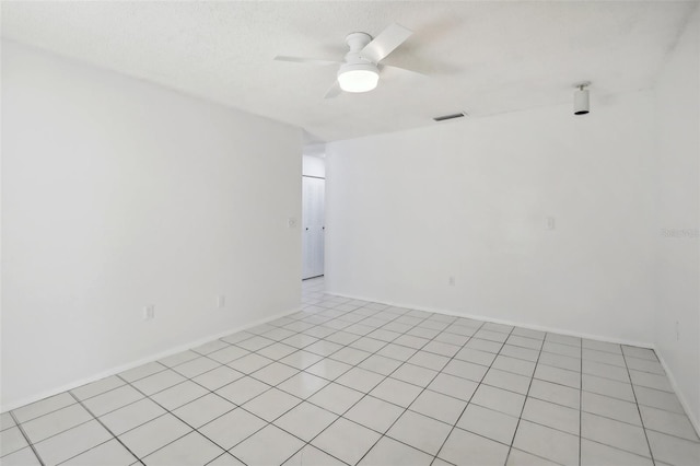 empty room featuring a textured ceiling, ceiling fan, and light tile patterned floors