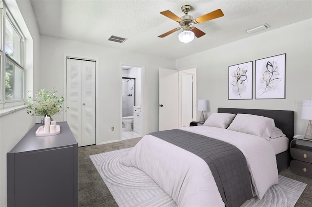 bedroom with ceiling fan, dark colored carpet, connected bathroom, and a textured ceiling