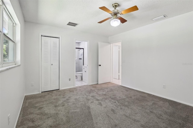 unfurnished bedroom with a closet, ceiling fan, ensuite bathroom, and light carpet