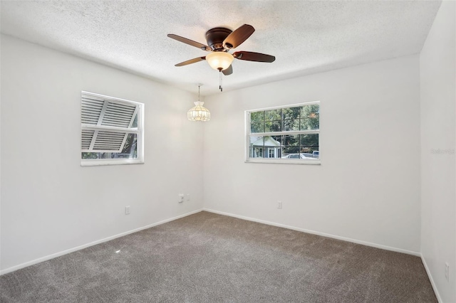 unfurnished room with a textured ceiling, ceiling fan with notable chandelier, and carpet floors