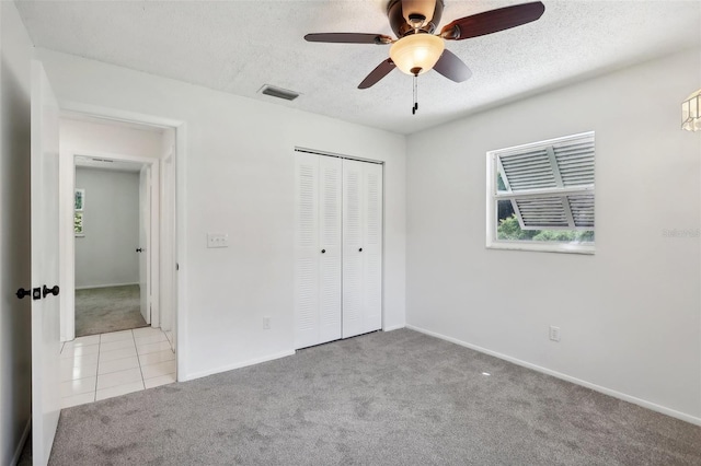 unfurnished bedroom featuring a textured ceiling, ceiling fan, light colored carpet, and a closet