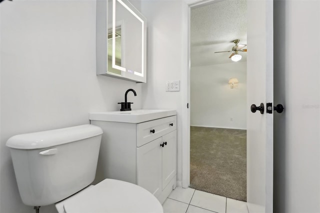 bathroom with a textured ceiling, vanity, toilet, tile patterned floors, and ceiling fan