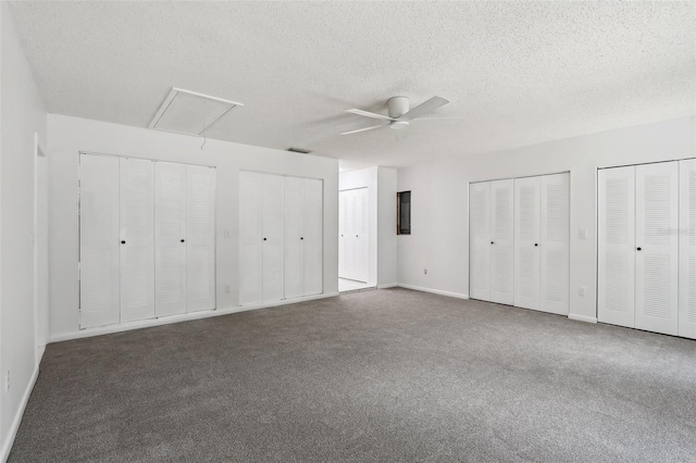 unfurnished bedroom with two closets, ceiling fan, and a textured ceiling