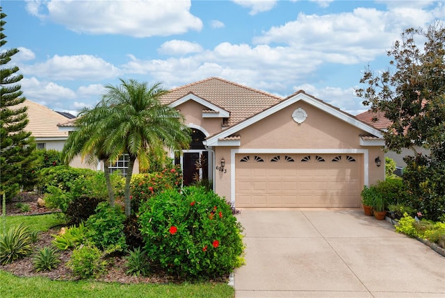 view of front facade featuring concrete driveway, stucco siding, a garage, and a tiled roof
