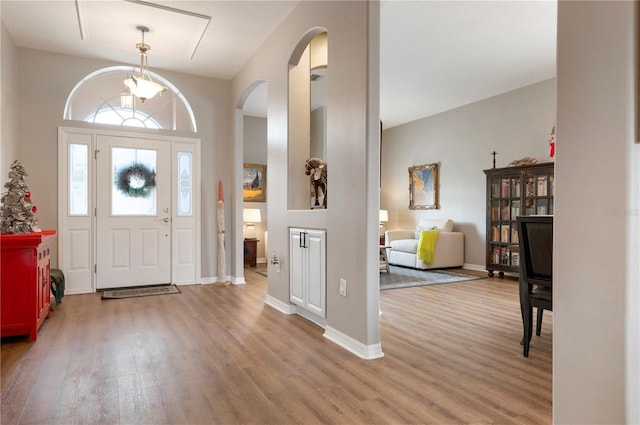 entryway featuring arched walkways, wood finished floors, and baseboards