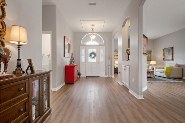 entrance foyer with light wood-style floors, baseboards, and arched walkways