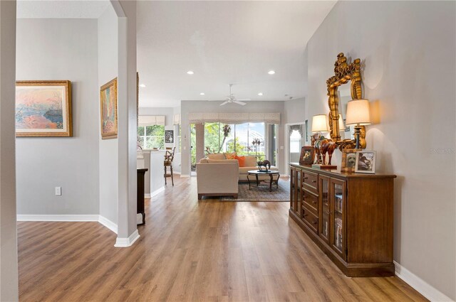 corridor with wood finished floors, baseboards, and recessed lighting