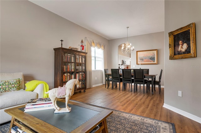 living area featuring a chandelier, baseboards, and wood finished floors