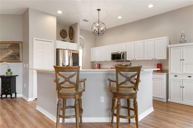 kitchen featuring appliances with stainless steel finishes, backsplash, white cabinets, light countertops, and recessed lighting