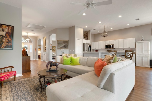 living room with light hardwood / wood-style floors and ceiling fan with notable chandelier