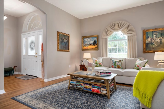 living room with wood finished floors, baseboards, and arched walkways