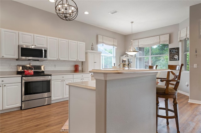 kitchen featuring stainless steel appliances, light wood-type flooring, backsplash, light countertops, and white cabinetry