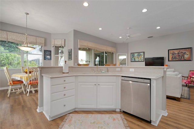 kitchen with stainless steel dishwasher, a sink, open floor plan, light countertops, and recessed lighting