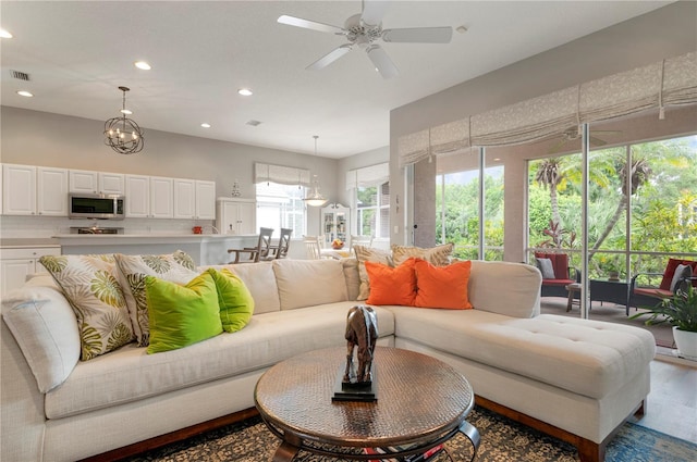 living area with recessed lighting, a ceiling fan, wood finished floors, and a chandelier