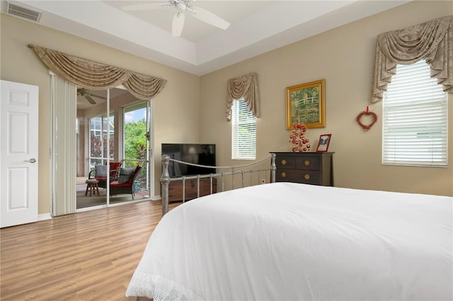 bedroom featuring a tray ceiling, wood-type flooring, and ceiling fan