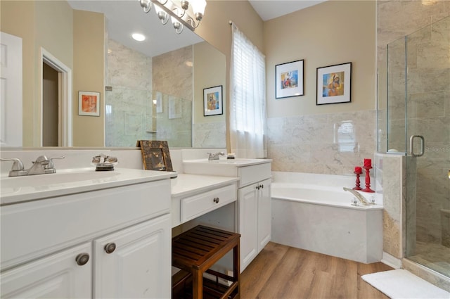 full bathroom with a stall shower, wood finished floors, a garden tub, and two vanities