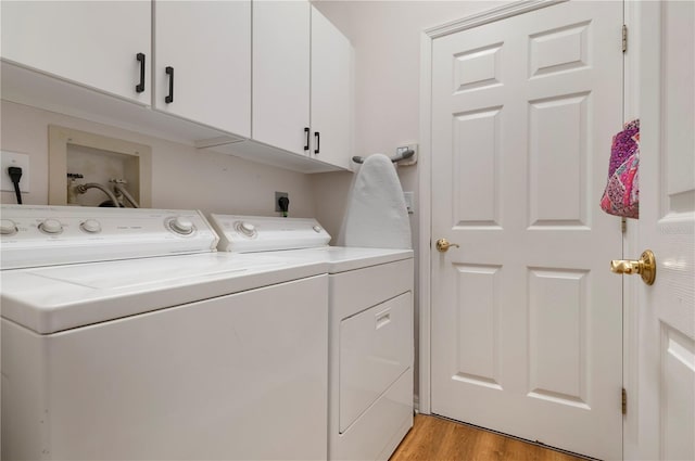 clothes washing area featuring cabinet space, washer and dryer, and light wood-style flooring