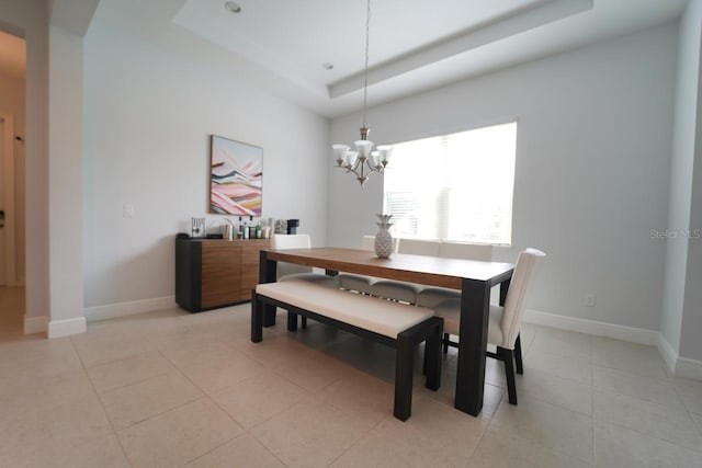 dining space with a tray ceiling, light tile patterned floors, and a chandelier