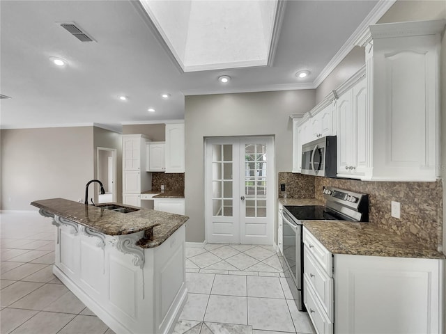 kitchen featuring a kitchen island with sink, dark stone countertops, sink, appliances with stainless steel finishes, and white cabinets