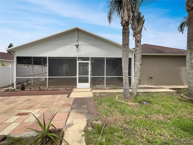 view of front of house featuring stucco siding, a patio, fence, and a sunroom